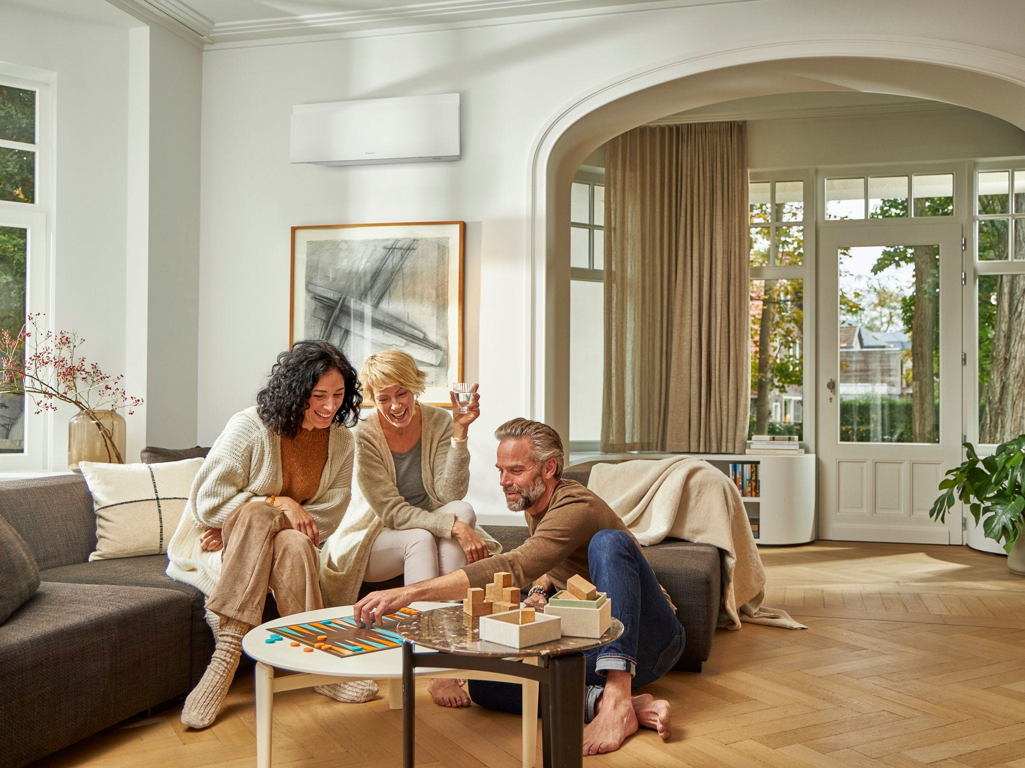 People round coffee table playing game Daikin Aircon on wall