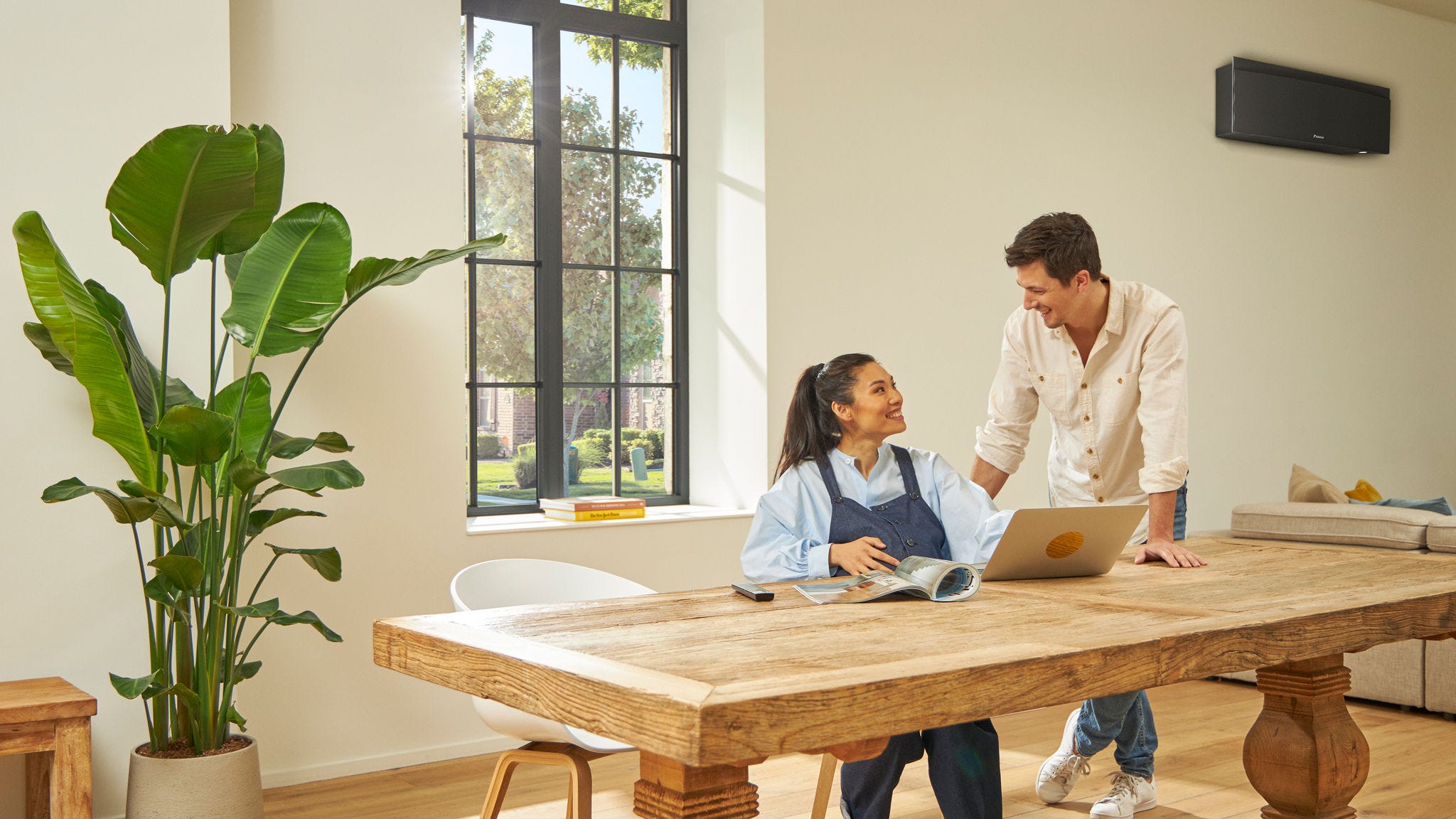 Pregnant couple smiling and talking while the woman is looking something up on her laptop under a Stylish unit in black