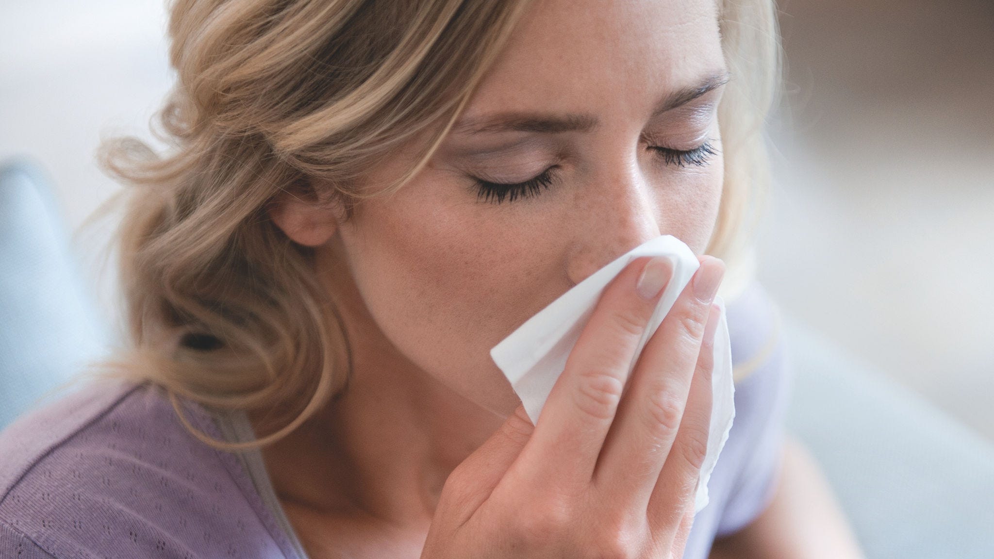 Woman blowing her nose due to pollen allergy