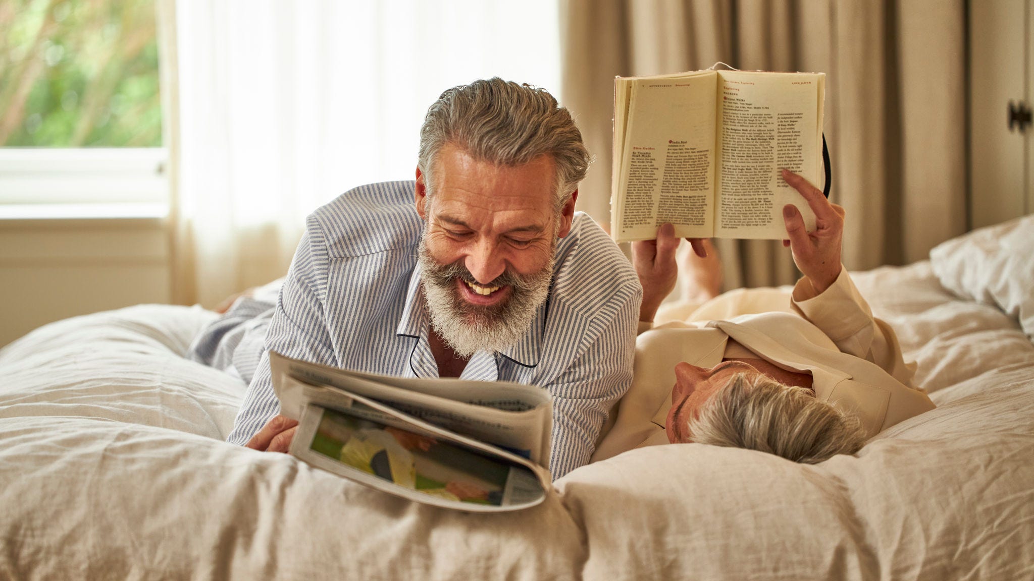 Middle-aged couple reading and relaxing on their bed while enjoying good indoor air quality