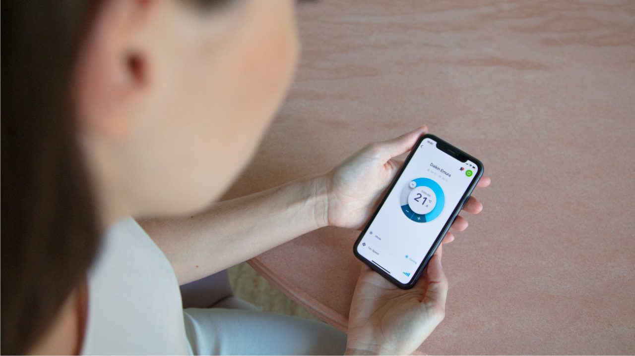 Man sitting on a sofa at home checking the Onecta app on his mobile phone