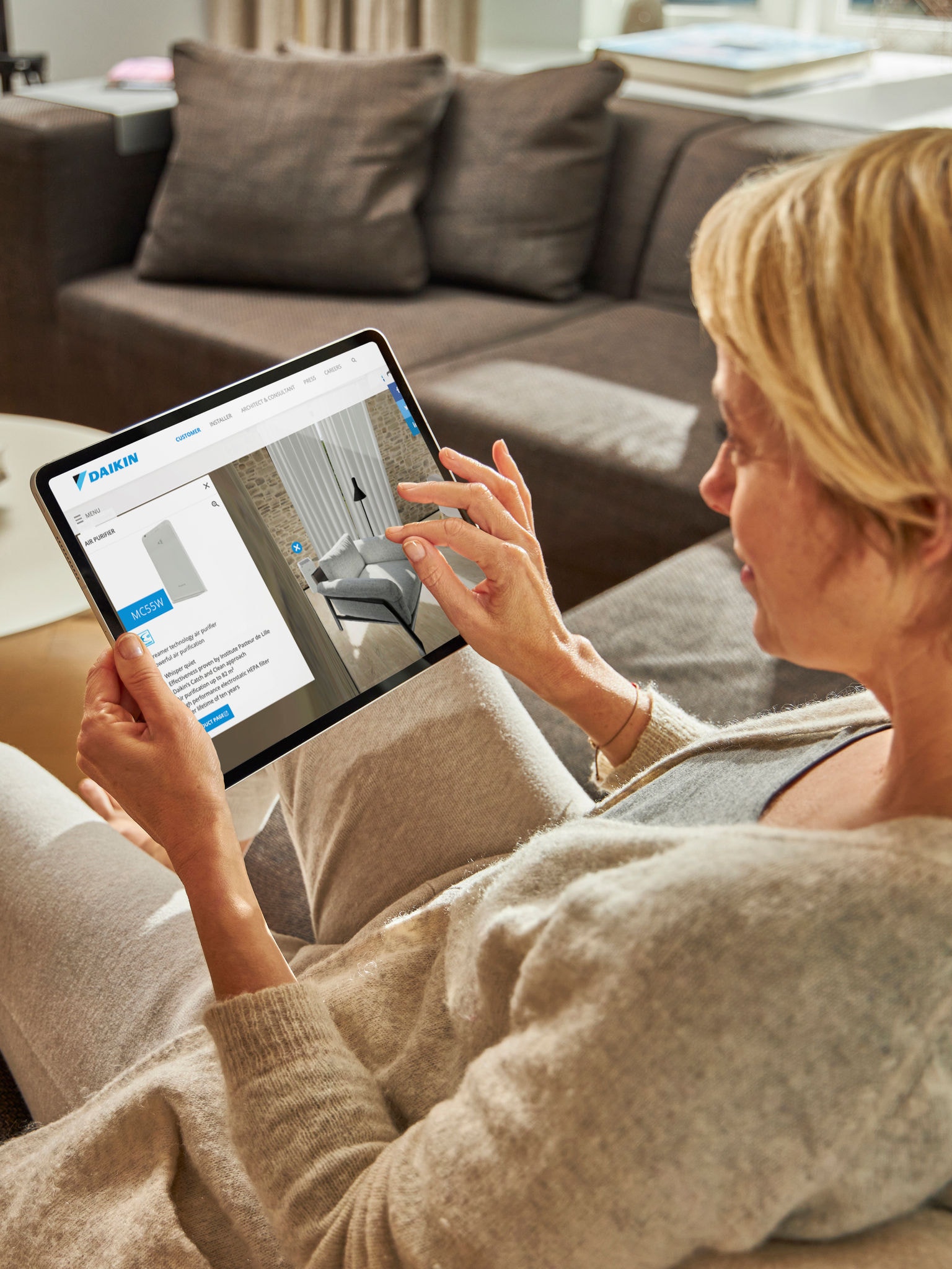 Woman visiting the virtual experience centre on her tablet while relaxing on her couch