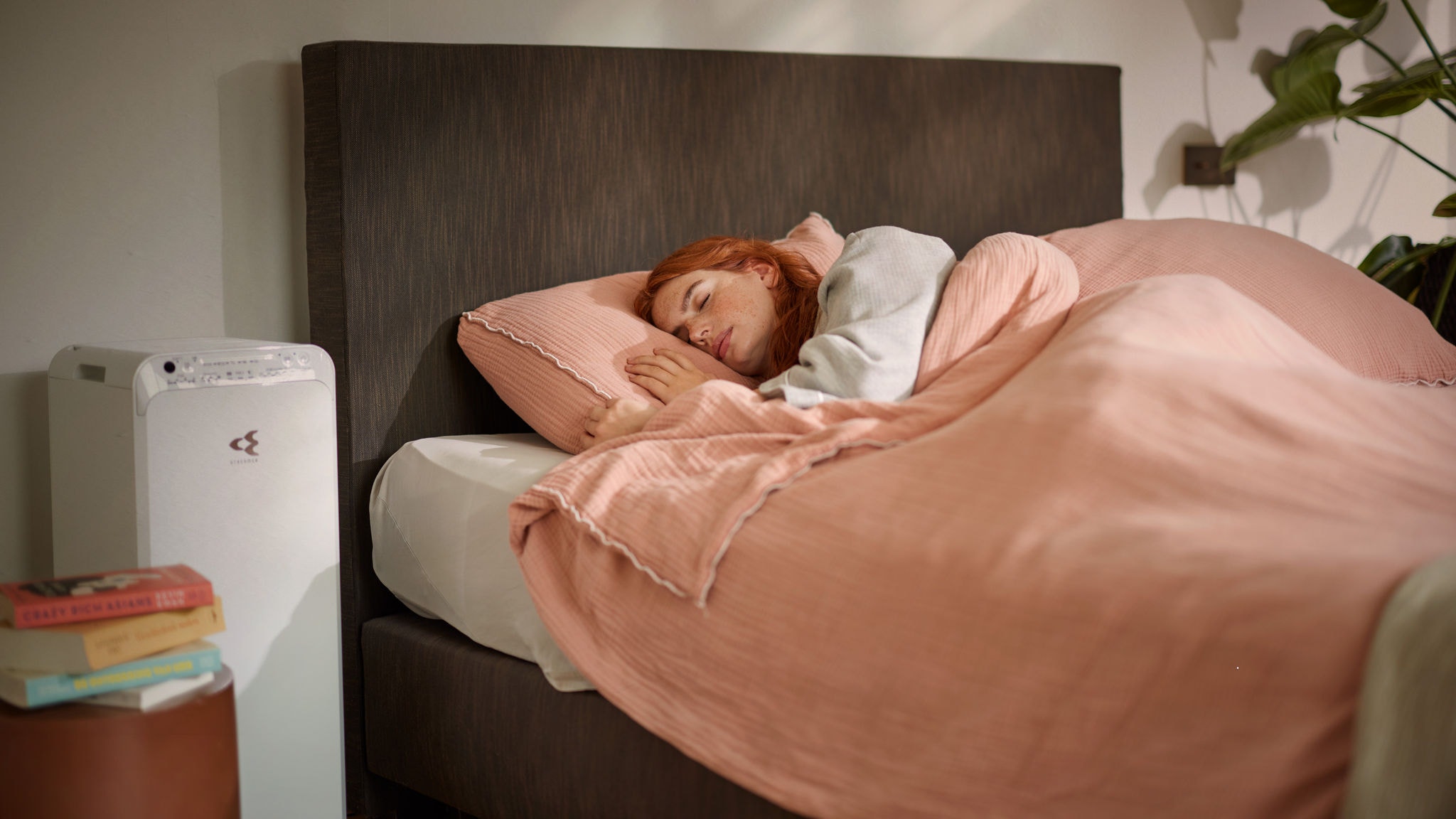 Woman sick in bed because of allergies has put on her air purifier