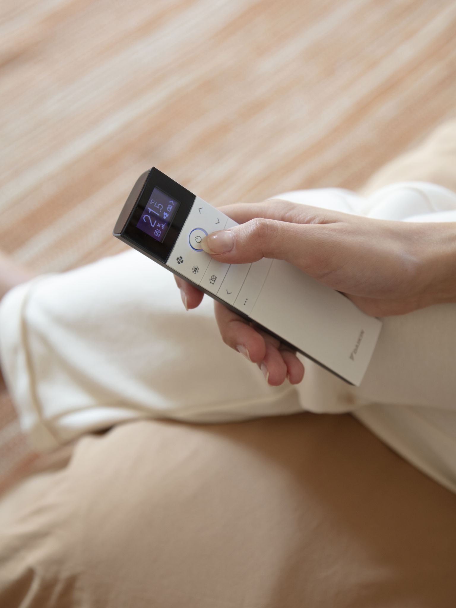 Woman controlling her climate technology with a remote from her couch
