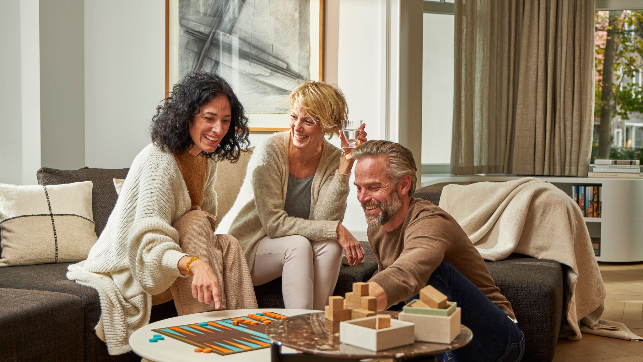 Two woman and a man playing a board game