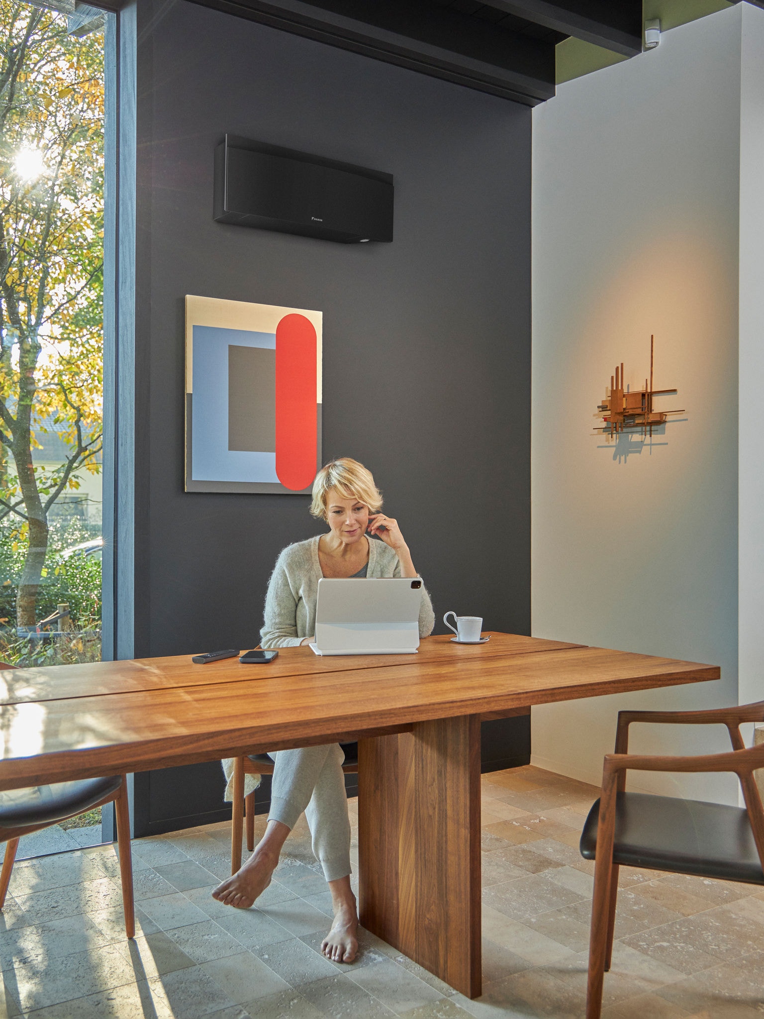 Woman using tablet in dining room with wall mounted air conditioner