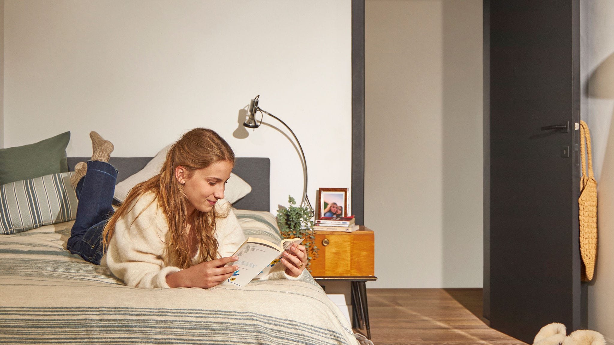 Woman relaxing on bed in a quiet home with low-noise heat pump comfort