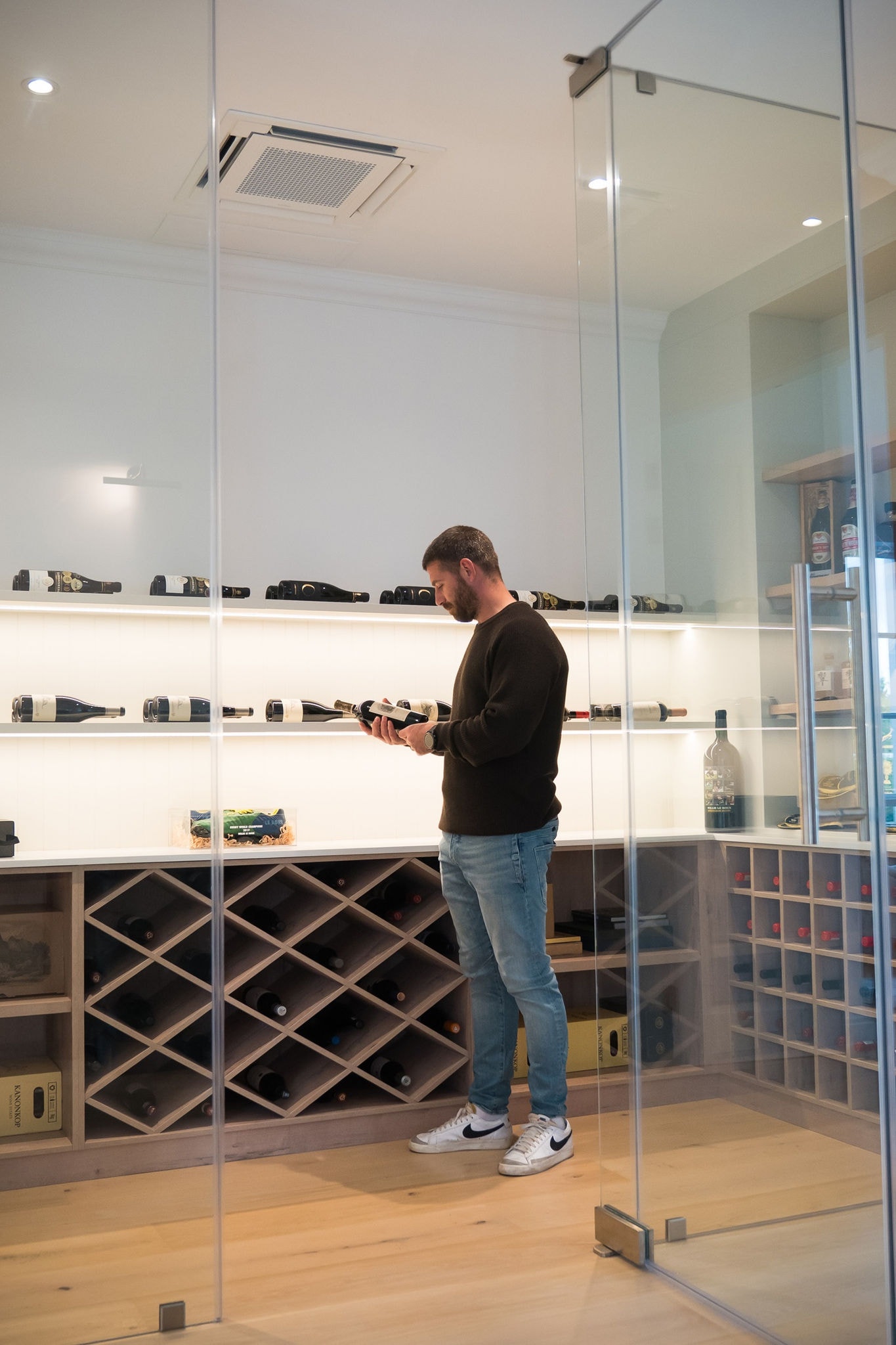 Willie Le ROux holding wine bottle with Daikin in wine cellar