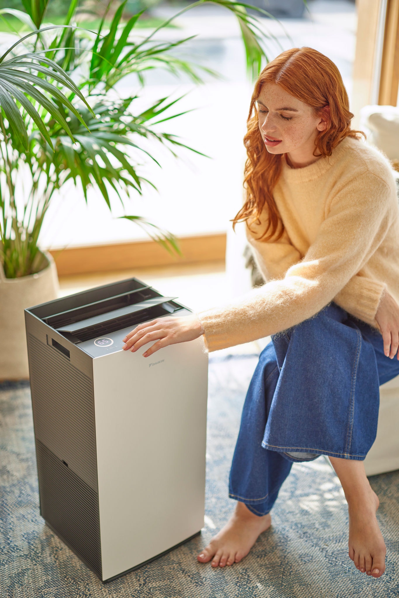 Woman relaxing in armchair using air purifier for cleaner indoor air