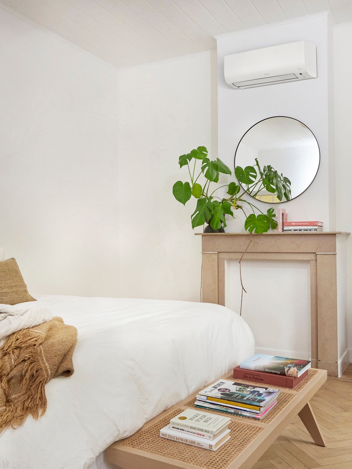 Daikin Aircon Sensira on wall in room with white linen