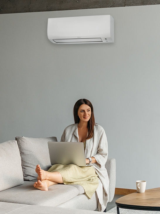 Woman sitting peacefully on couch with Senira Air conditioner