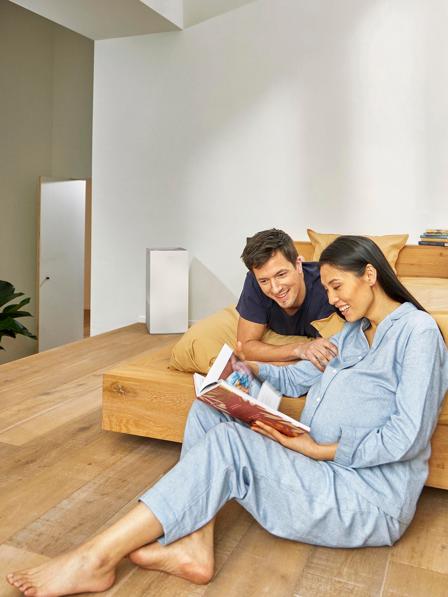 Couple relaxing in bedroom with air purifier improving indoor air quality