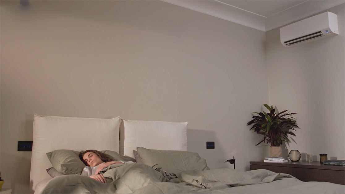 Woman peacefully sleeping with her Daikin unit in quiet night mode