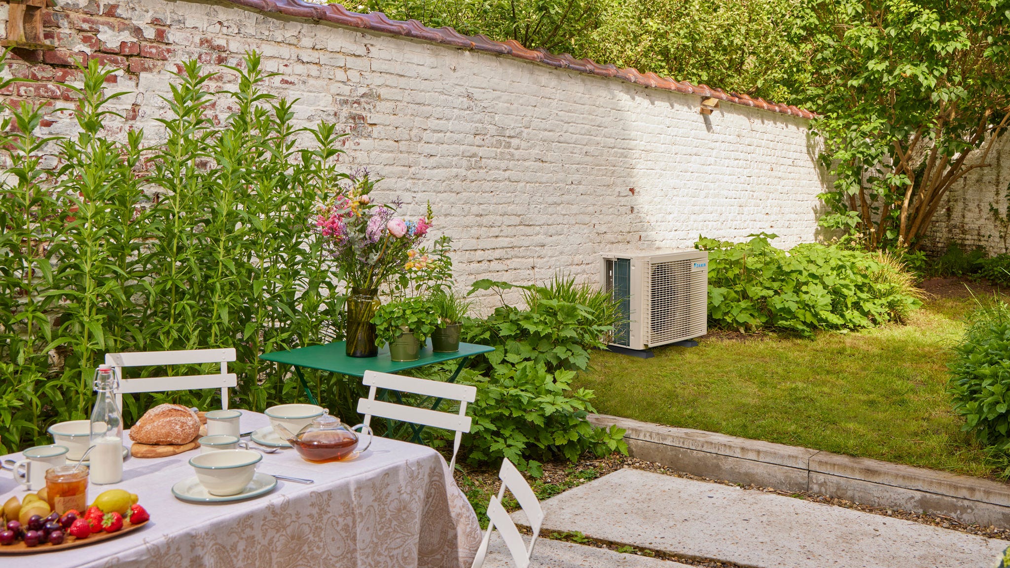 Garden breakfast setting with inverter air conditioner cooling nearby home