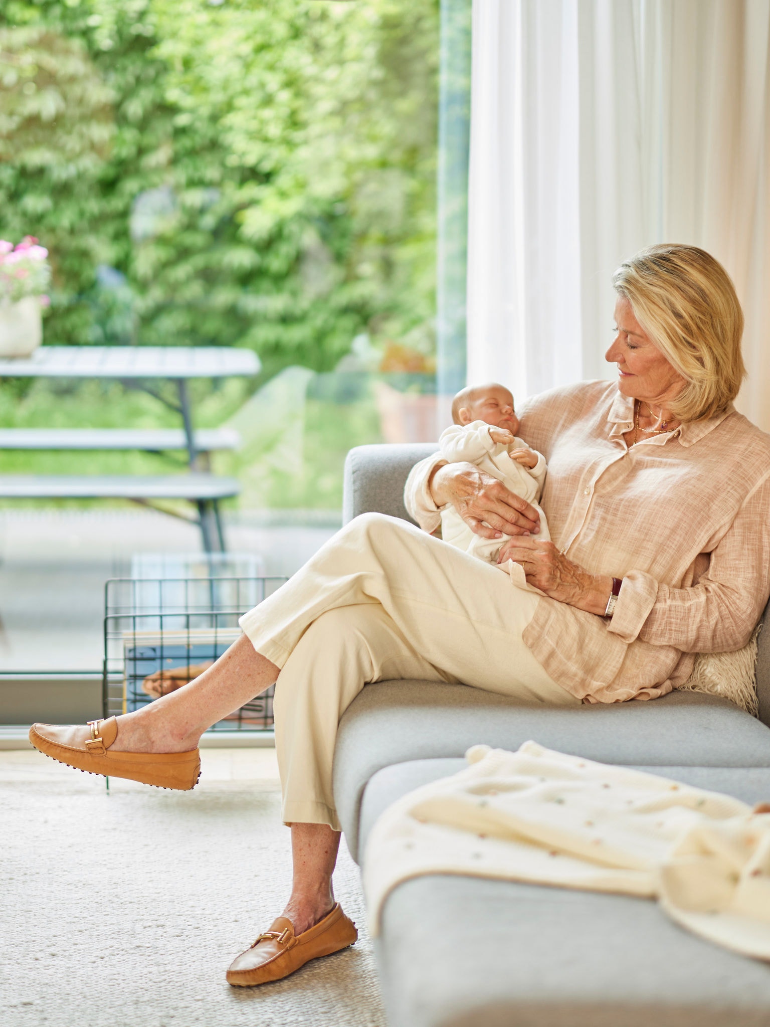 Woman holding a baby while sitting on a sofa in a comfortably heated room.