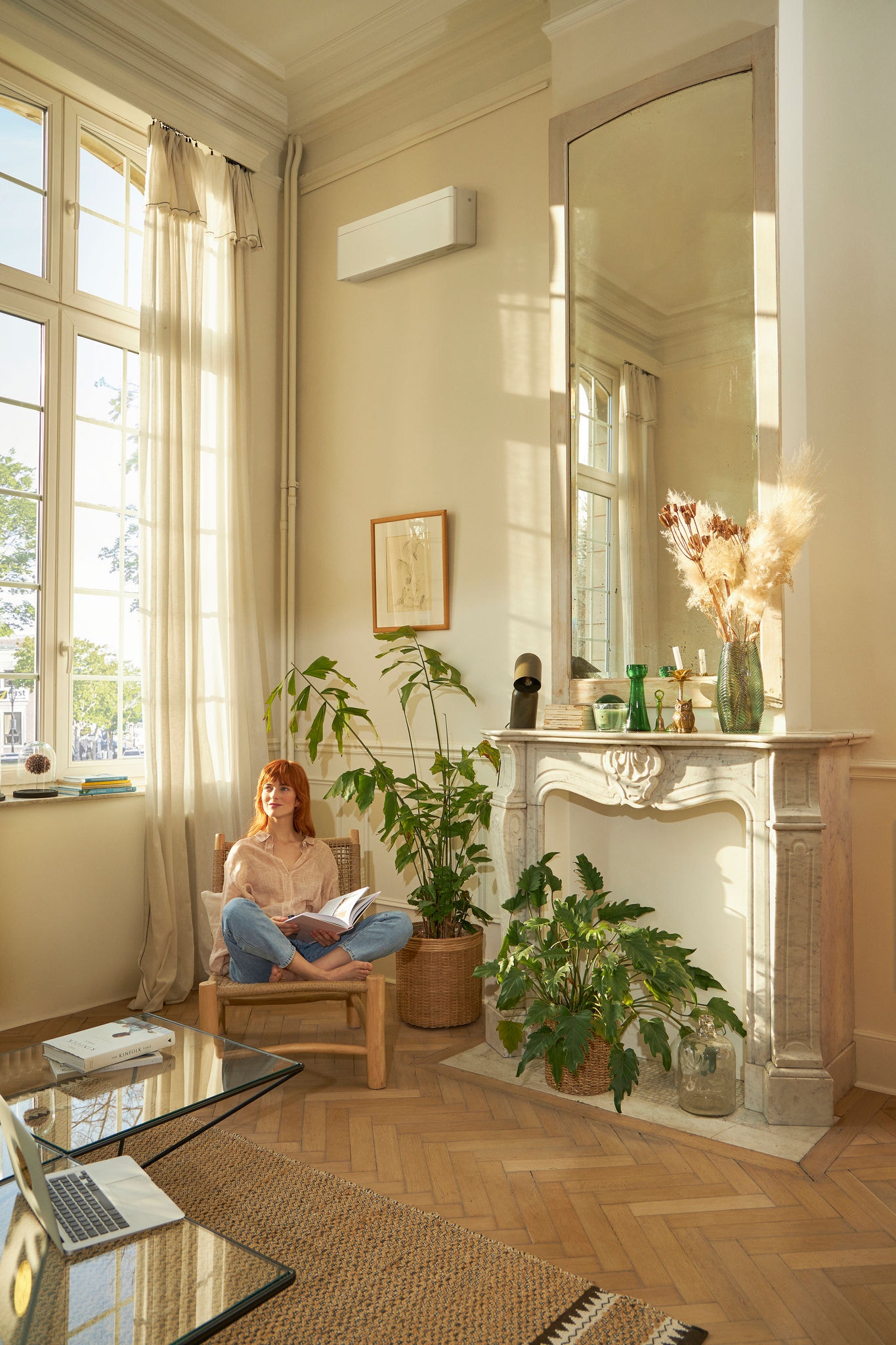Woman reading magazine in plant-filled room with inverter air conditioner