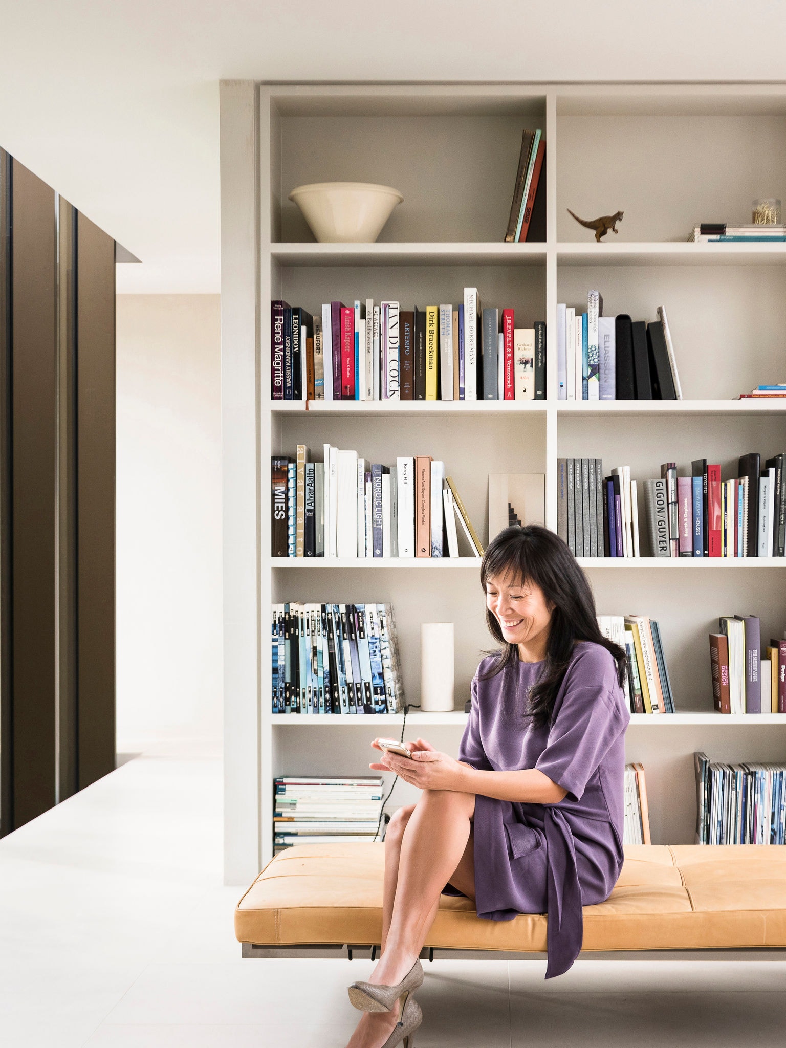 Woman controlling wall-mounted heat pump via smartphone in a modern energy-efficient home